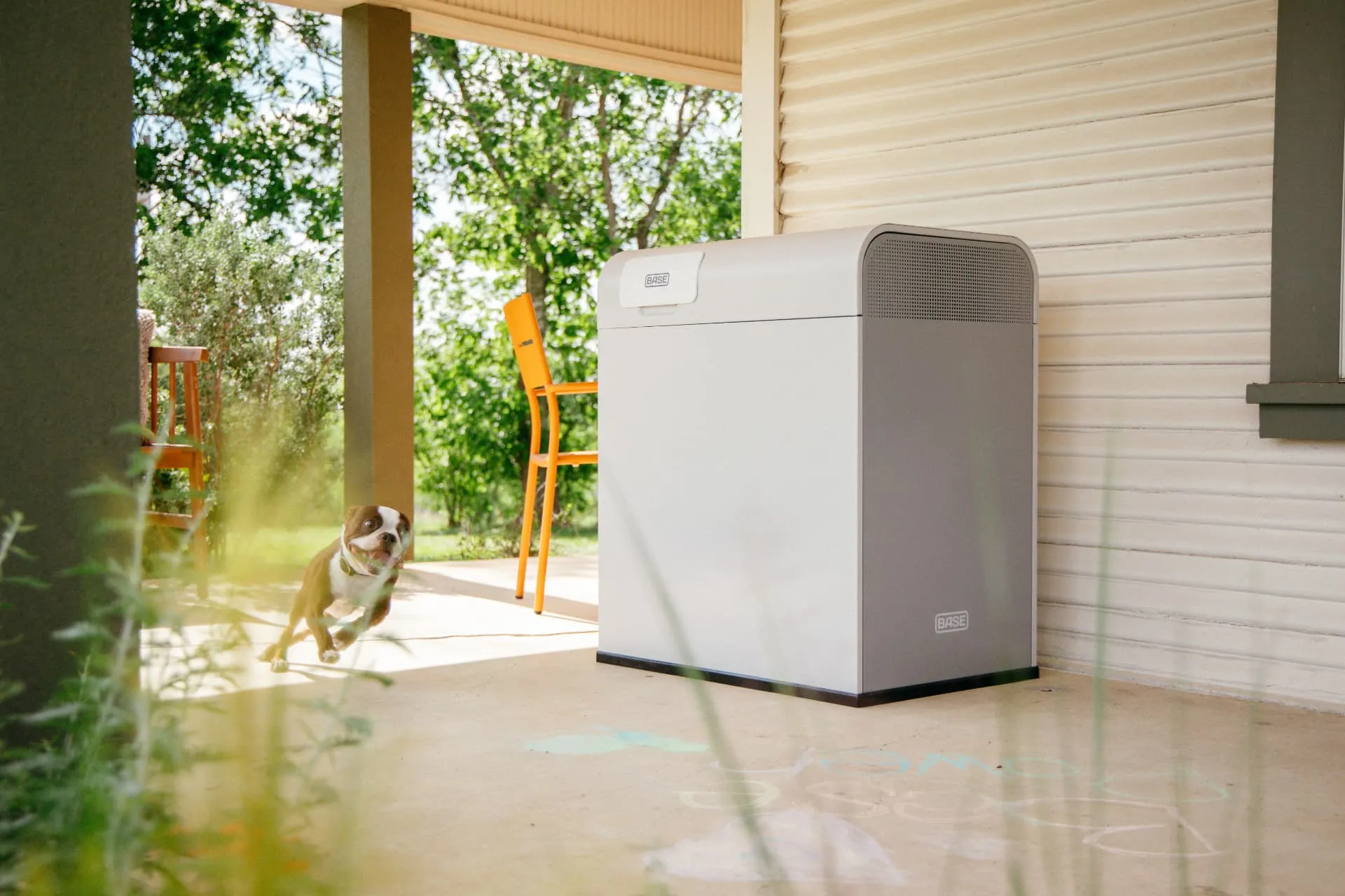 Base Power home battery installed on a sunny Texas porch while a dog runs past
