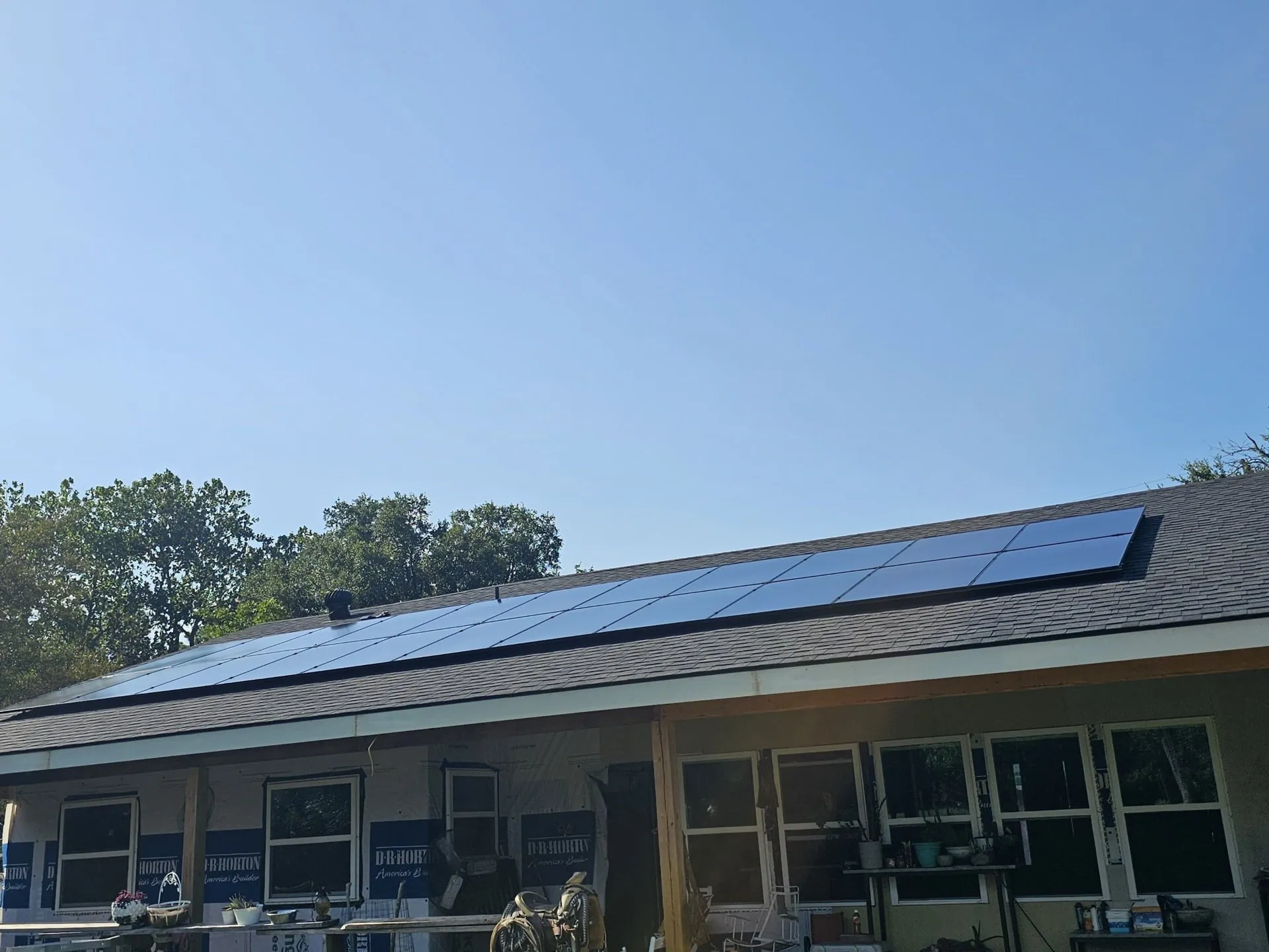 Texas ranch style home with a full array of CW Enerji all-black solar panels on a shingle roof under a clear blue sky