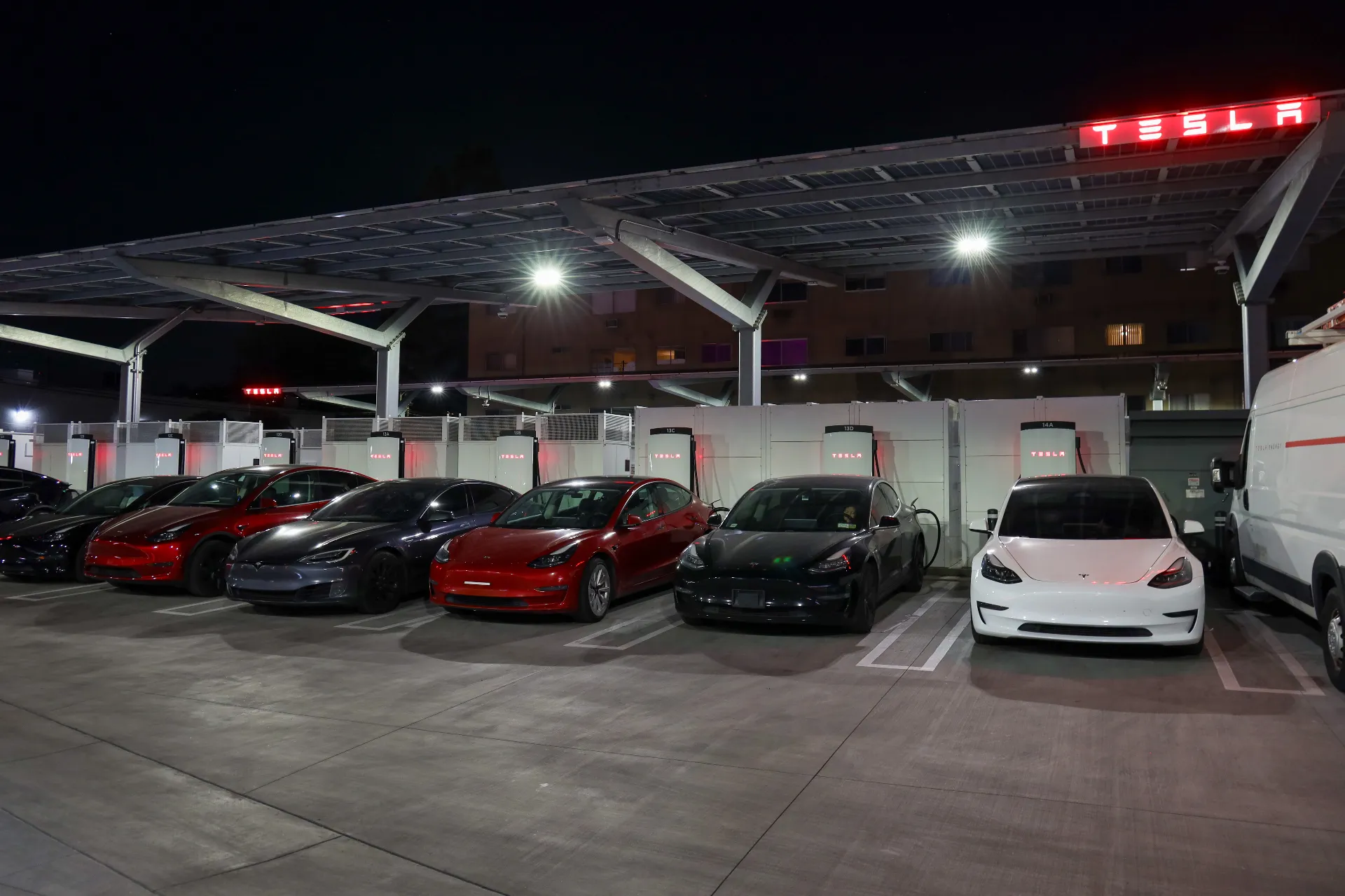 Tesla Supercharger station with multiple vehicles charging at night