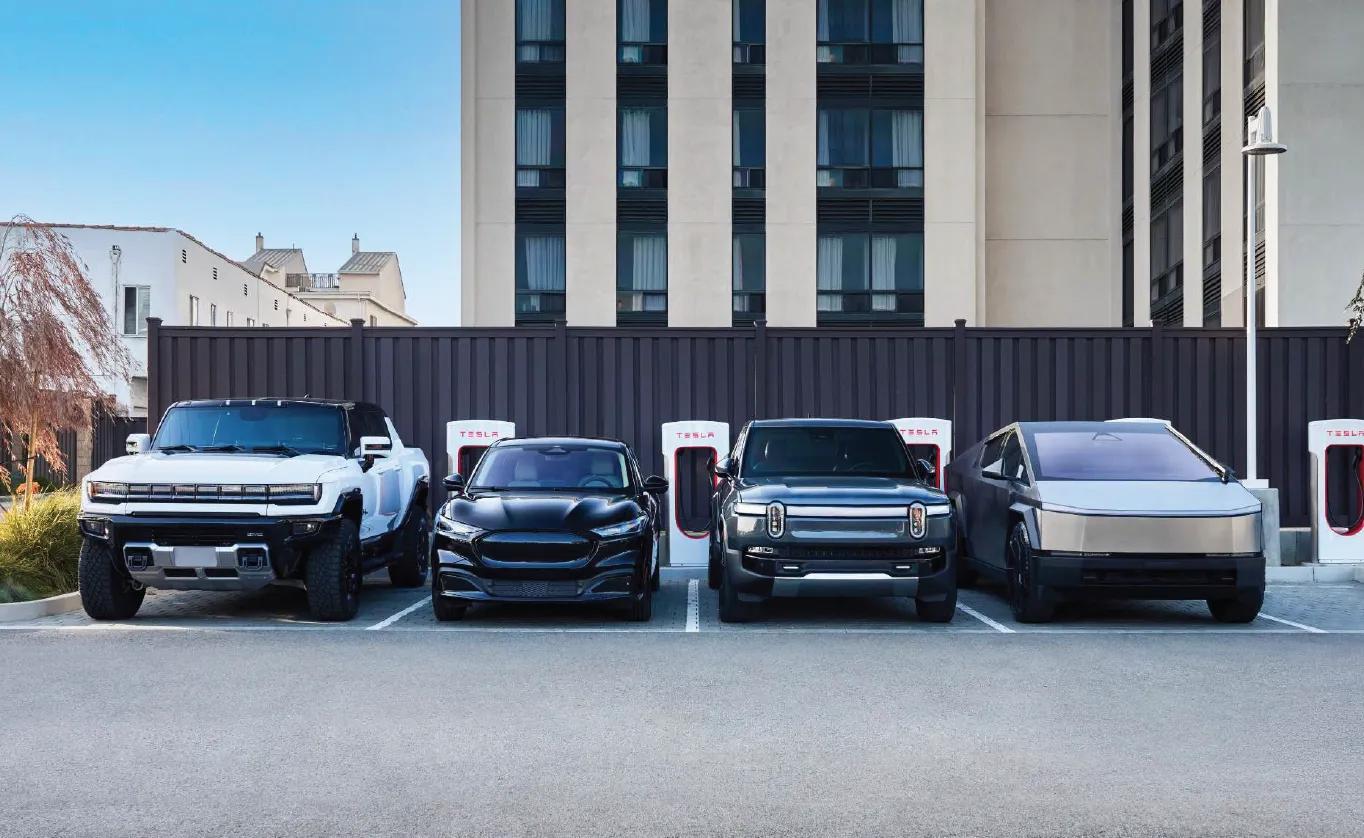 GMC Hummer EV, Ford Mustang Mach-E, Rivian R1T, and Tesla Cybertruck charging side by side at Tesla Supercharger stalls