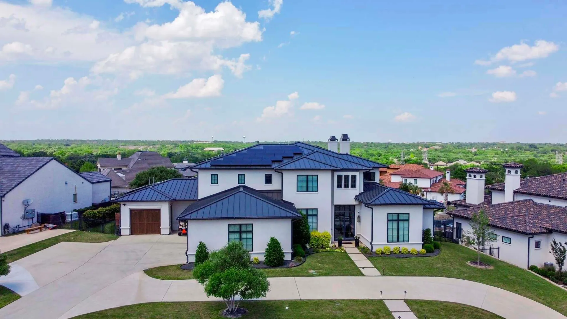 Modern Texas home with a metal roof and rooftop solar panels installed by Good Faith Energy on a sunny day
