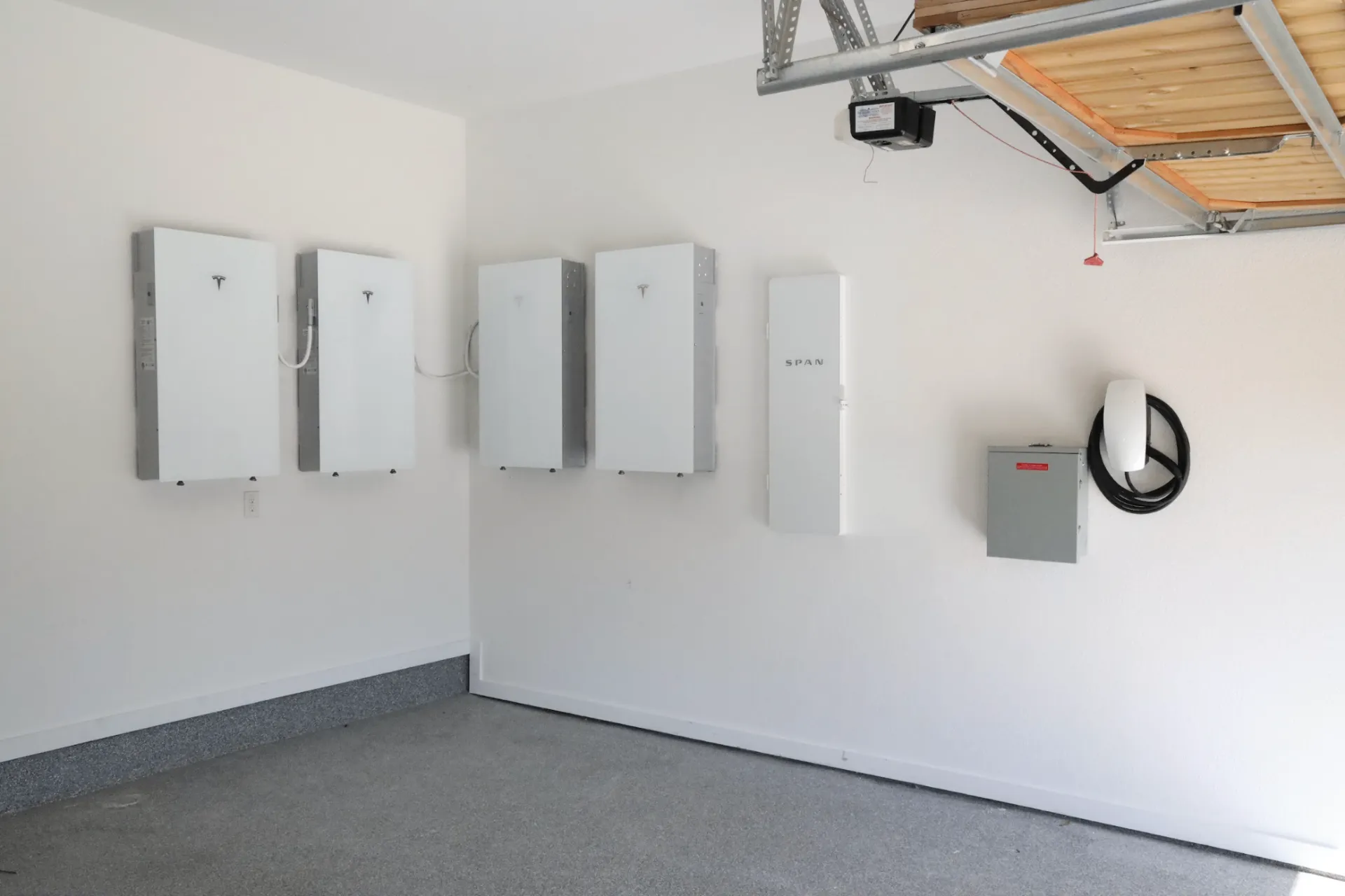 Four Tesla Powerwall batteries with a SPAN smart panel and Tesla Wall Connector EV charger installed in a Texas garage by Good Faith Roofing