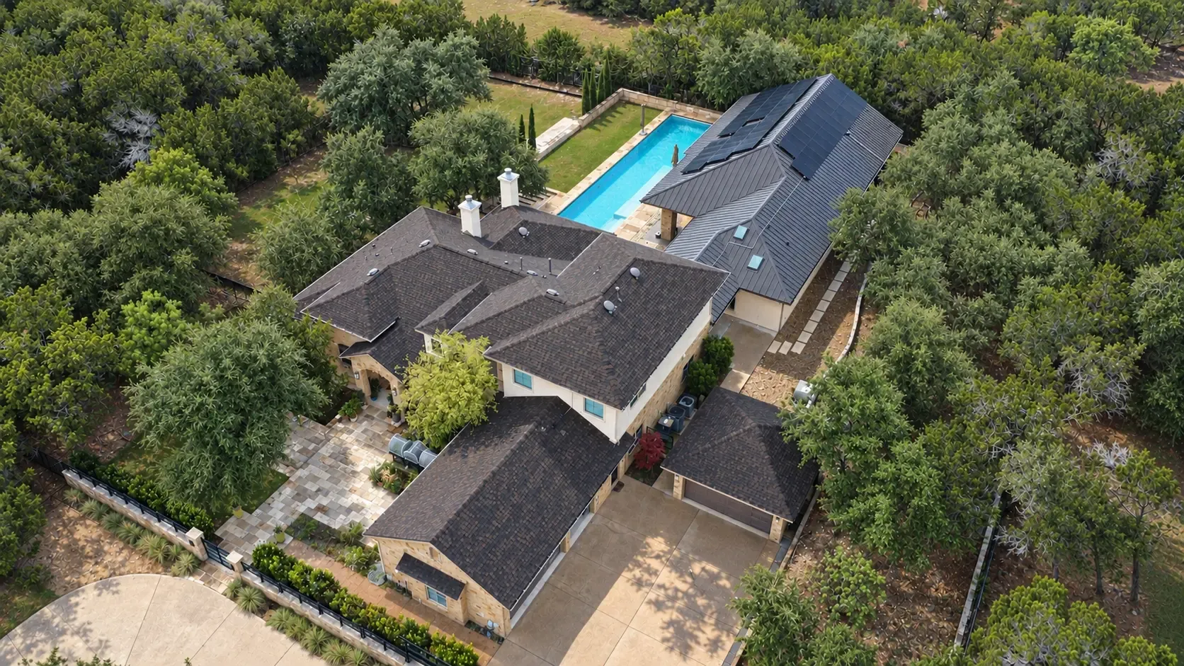 Aerial view of a Texas estate with a newly installed shingle roof and a metal roof with rooftop solar panels installed by Good Faith Energy