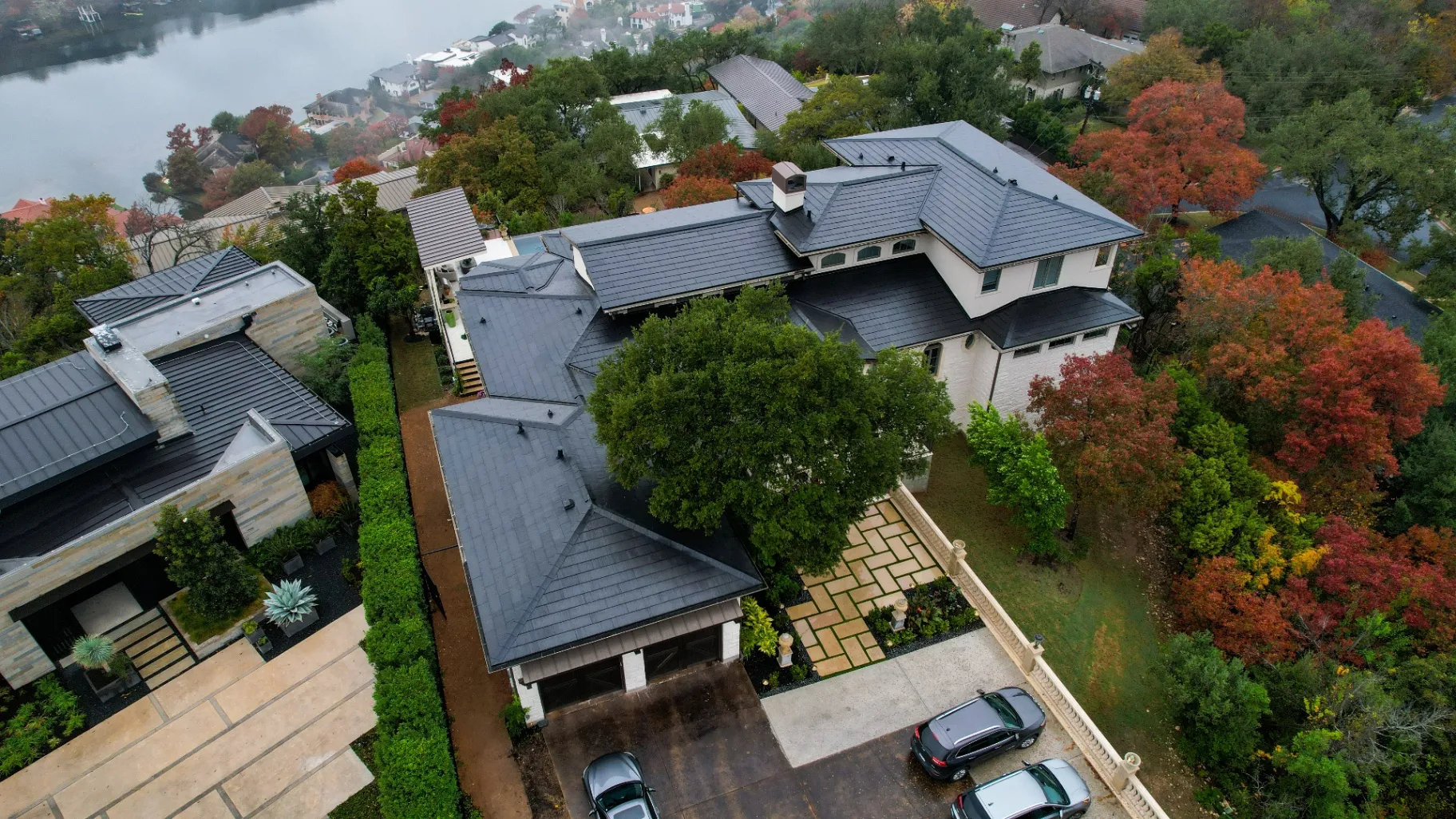 Aerial view of luxury Texas home with sleek Tesla Solar Roof installation overlooking the lake