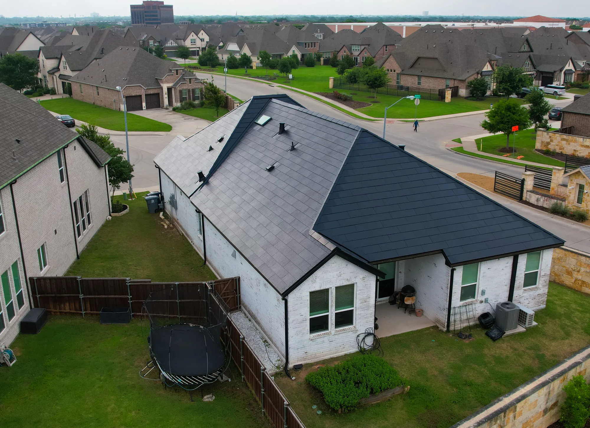 Tesla Solar Roof contrasted with neighboring shingle roofs in a Texas suburb