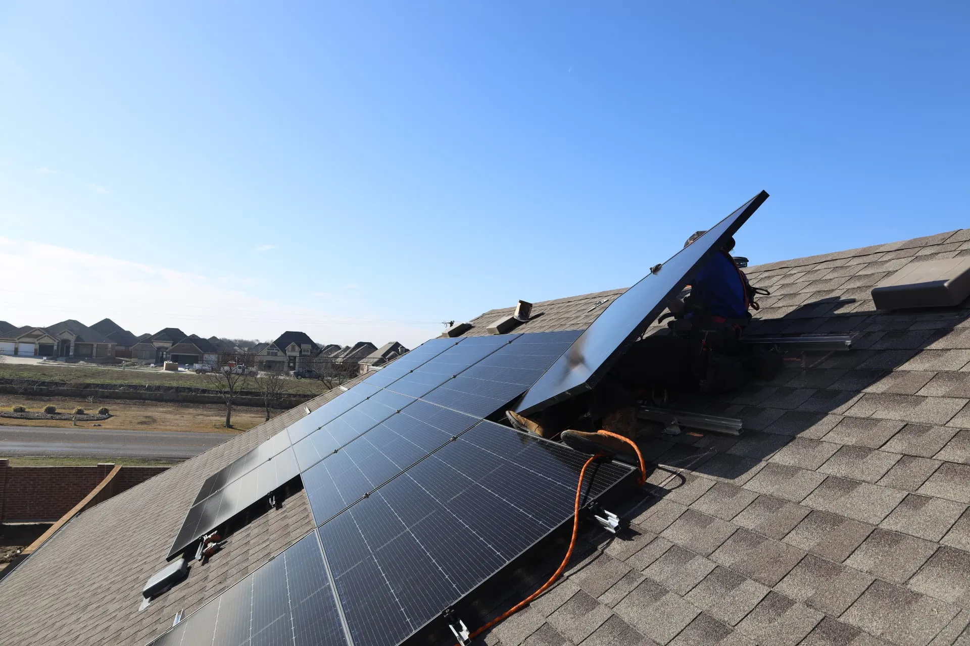 Good Faith Energy technician servicing solar panels on a Texas home rooftop on a sunny day